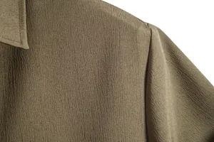 Macro view of textured fabric and shoulder seam on olive green casual shirt for men