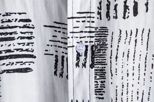 Macro detail of men's casual shirt featuring abstract print and white button texture
