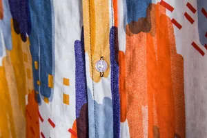 Close-up detail of a colorful abstract print shirt with a transparent button closure.
