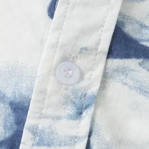 Macro detail of white button and placket on blue and white printed Hawaiian shirt