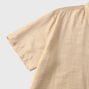 Detailopname van de lichte, getextureerde stof van een beige herenoverhemd met korte mouwen