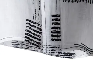 Close-up view of high-quality stitching and curved hem on a men's abstract print shirt.