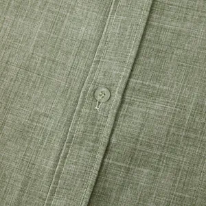 Detailed macro shot of green linen-cotton shirt fabric texture and button sewing.