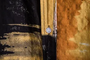 Macro detail showing button and vibrant yellow floral pattern on men's summer shirt fabric