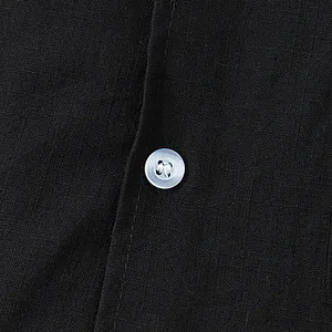 Close-up of a white button on black cotton-linen fabric showing detailed weave texture