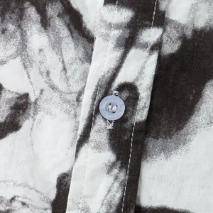 Macro detail of transparent button on a black and white floral Hawaiian shirt
