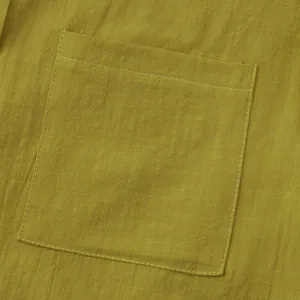 Macro detail of the front chest pocket and breathable linen fabric on men's yellow shirt
