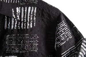 Close-up of black men's casual shirt featuring white abstract line print and textured fabric.