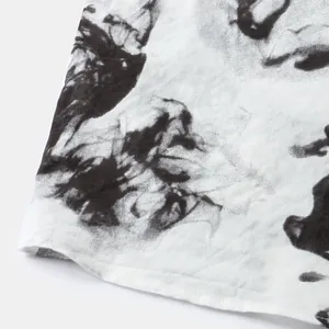 Close-up detail of white men's short sleeve shirt featuring black ink abstract print pattern