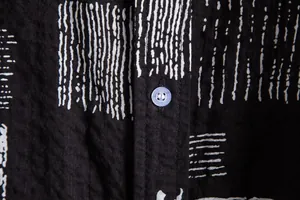 Detail macro shot of black casual shirt fabric with white stripes and clear button.