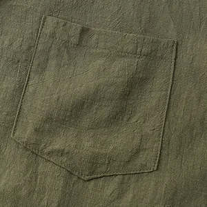 Close-up of olive green cotton linen shirt pocket showing natural textured fabric weave