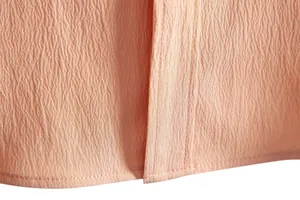 Detailed macro view of peach men's shirt showing crepe fabric and professional stitching