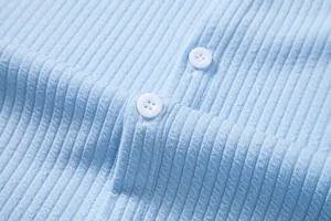 Close-up macro view showing the blue ribbed fabric texture and white buttons on a casual shirt
