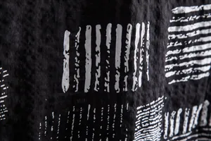 Close-up of black shirt fabric featuring white abstract stripes and crinkle texture