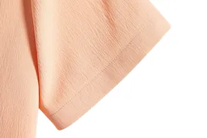Close-up of light orange men's shirt sleeve showing fabric texture and stitching.