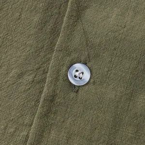 Close-up of olive green cotton linen fabric texture and button detail on men's shirt