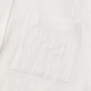 Detailed macro view of the chest pocket on a breathable white cotton linen shirt