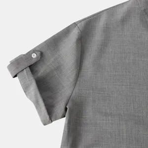 Detalle del puño con botón en una camisa gris de manga corta para hombre con cuello levantado