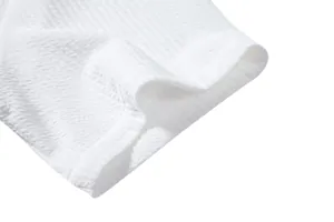 Close-up macro view of the white textured seersucker fabric on a men's casual shirt hem