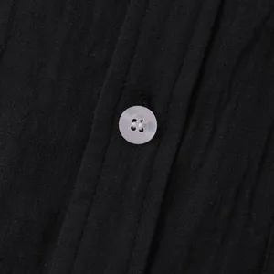 Close-up macro view of black cotton linen shirt fabric texture and a white button detail
