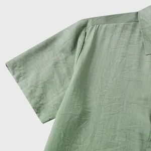Detailopname van een saliegroen shirt met korte mouwen met fijne stoftextuur en naden.
