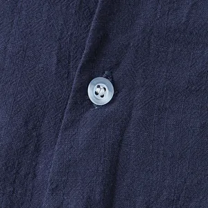 Detailed close-up view of the button and fabric texture on a navy blue cotton linen shirt