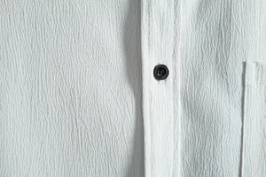 Close-up detail showing the textured fabric and button of a men's casual shirt.