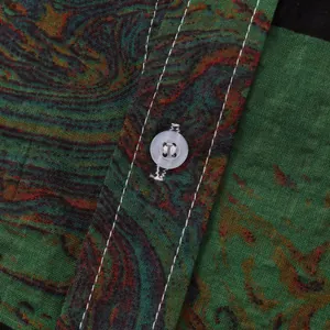 Makroansicht eines Herren-Hawaiihemdes mit lebhaftem Paisleymuster und Knopf.