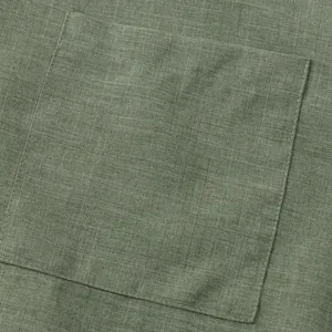 Primer plano de camisa de lino verde oliva que muestra costuras de bolsillos y textura.