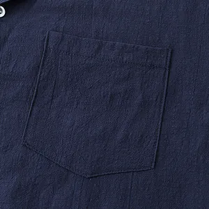 Macro detail of a navy blue cotton linen shirt showing pocket and fabric texture