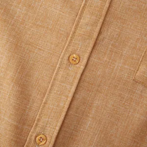Detailed macro view of ginger cotton linen fabric and buttons on a men's long-sleeved shirt