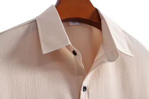 Close-up detail of beige men's casual shirt showing textured fabric and lapel collar