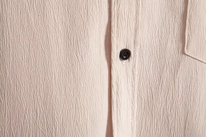 Close-up detail of textured crinkle fabric on men's beige casual button-up shirt
