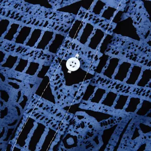 Detailopname van blauw-zwarte stof met etnisch patroon en witte knoop op een herenoverhemd