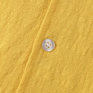 Macro detail of yellow linen shirt fabric showing weave texture and button