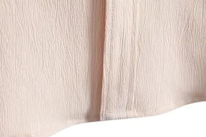 Detailed macro shot showing breathable crinkled fabric texture and precise stitching on men's shirt