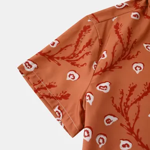Vue détaillée des motifs floraux rouges sur une chemise hawaïenne orange pour homme