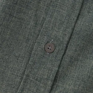 Primer plano detallado de la textura de tela de algodón y lino verde y botón de camisa