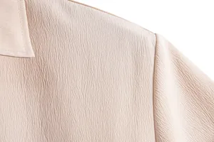 Close-up of beige men's shirt showing fine crinkle fabric texture and shoulder seam