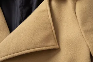 Macro detail of a classic camel wool coat showing lapel stitching and smooth black inner lining