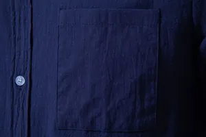 Close-up detail of navy blue cotton linen shirt pocket showcasing the breathable fabric texture