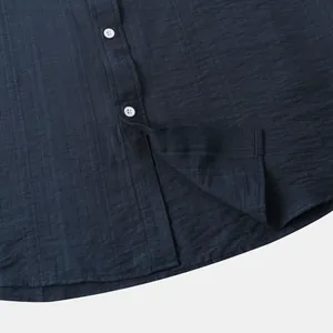 Detail van getextureerd donkerblauw herenoverhemd met witte knopen en een ronde zoom