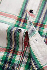 Primer plano de camisa de cuadros verde y blanca con detalle de botones y tejido