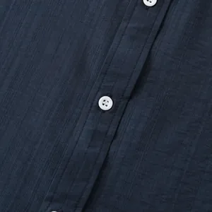 Detailopname van de marineblauwe linnen textuur en witte knopen op een casual herenoverhemd