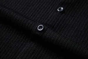 Macro detail of men's black ribbed knit shirt showing fabric texture and buttons