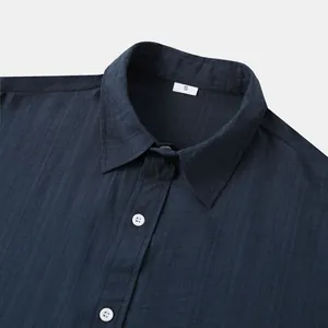 Detailopname van de kraag van een donkerblauw overhemd met korte mouwen.