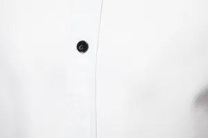 Macro detail of black button and neat stitching on white long sleeve casual shirt