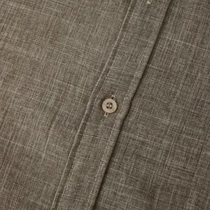 Detailed macro view of brown cotton linen fabric texture and button on men's shirt