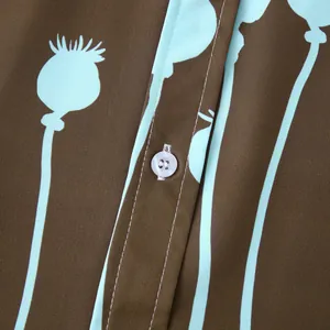 Gros plan sur l'imprimé floral bleu clair et le bouton blanc d'une chemise