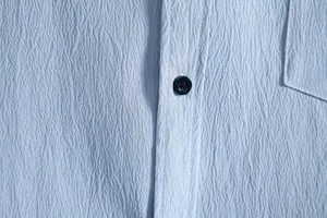 Close-up of light blue men's shirt showing crinkled fabric texture and button detail